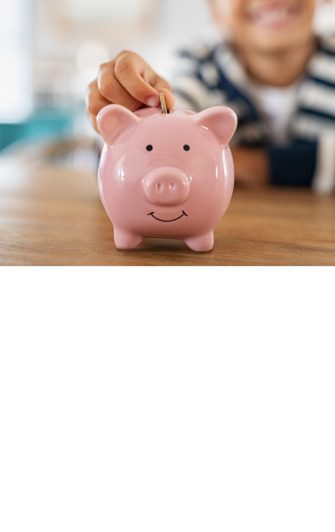 blurred background child placing a coin in a pink piggy bank that is focused in the foreground
