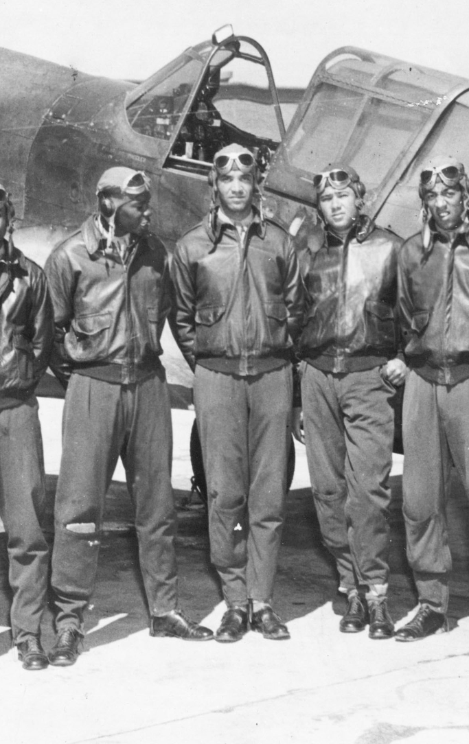 airmen of the tuskegee airmen flight school standing in front of a fighter plane